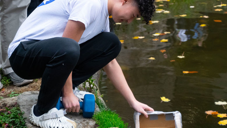 Student testing a prototype boat for the Cardboard Regatta