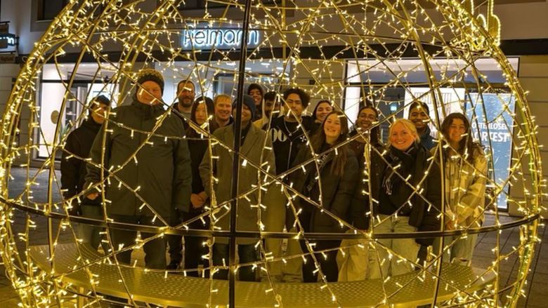 Students standing behind circular structure with twinkle light