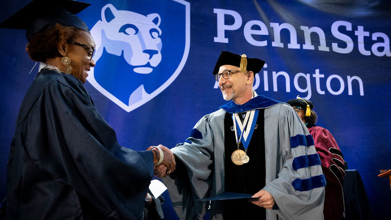 Interim Chancellor Andrew August presents a Penn State Abington student with her diploma