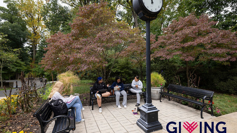 Students sitting on benches around a vintage clock