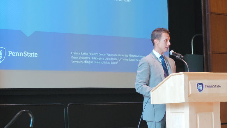 Glenn Sterner, a white man in a grey suit, standing at the podium.