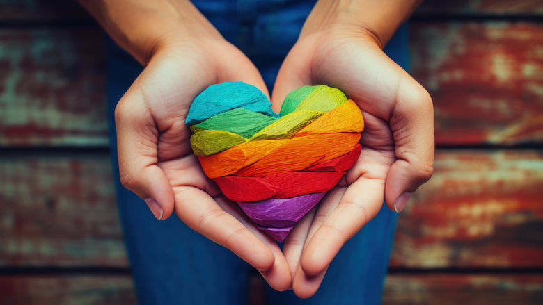 hand holding wooden rainbow heart