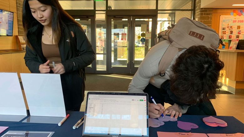 students standing at welcome desk inside lions gate
