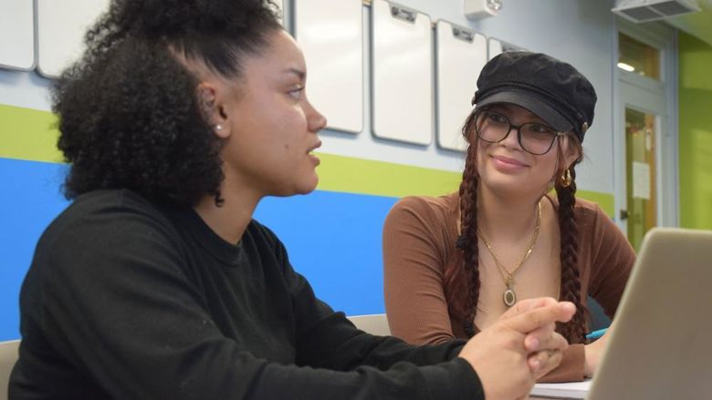 Two student talking with a laptop in front of them