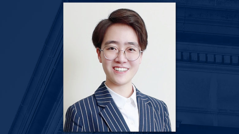 A headshot of a person wearing glasses on a blue background.