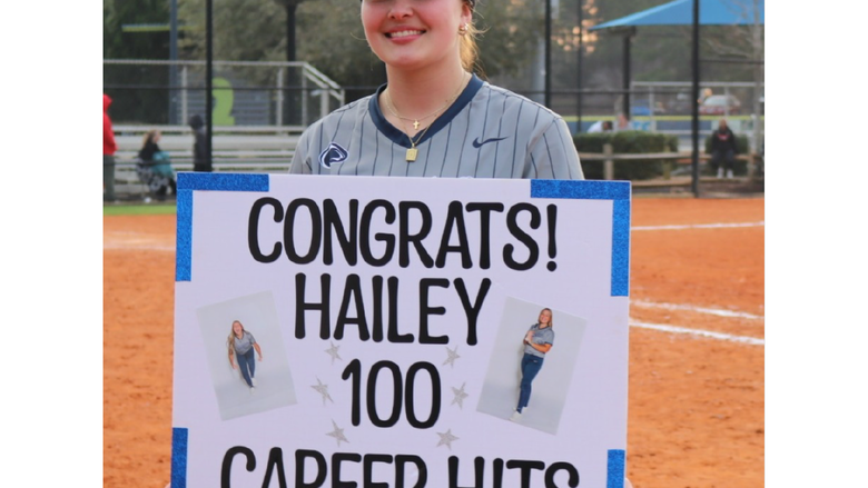 Athlete holding sign reading "Congrats Hailey 100 Career Hits"