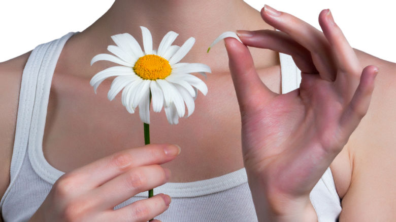young woman picking petals off daisy