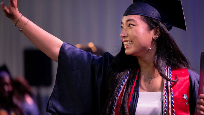 Woman in cap and gown waving