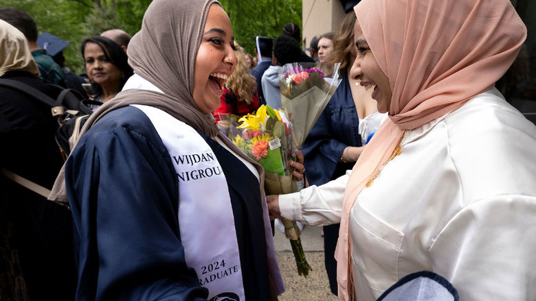 Two women celebrate after graduate ceremonies