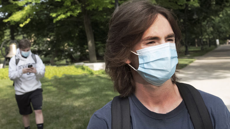 Two students wear walk across campus at University Park wearing face masks.