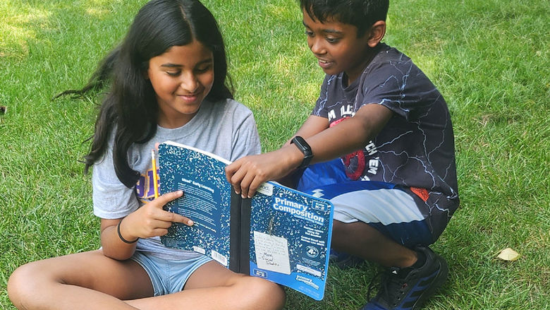 Two children reading a copybook