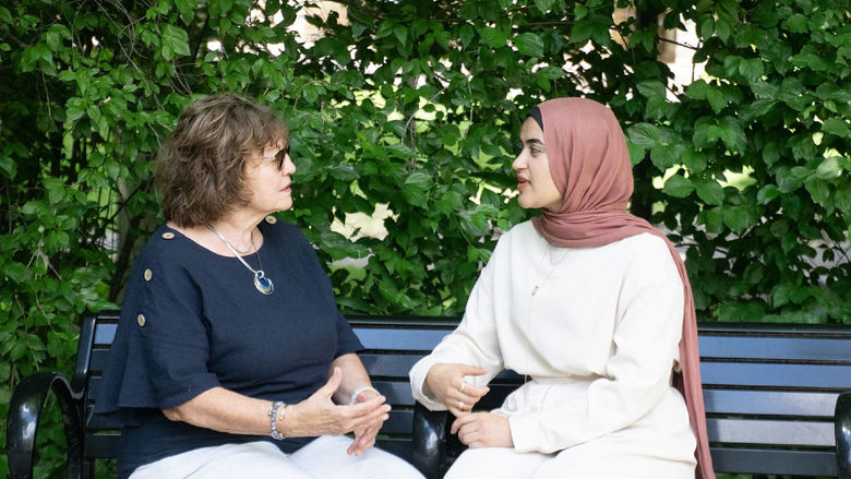 Two women sitting on a bench and talking