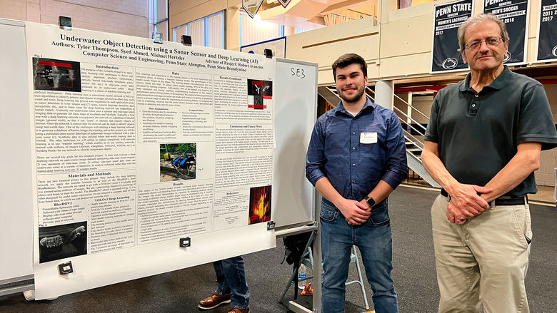 Student and professor stand next to research poster