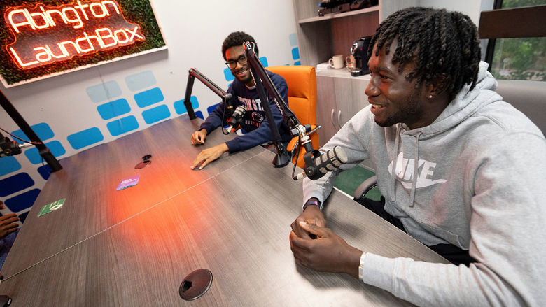 Two male students speaking into microphones to record a podcast in the Abington LaunchBox