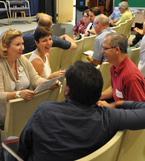 Faculty members sit in small groups discussing and laughing