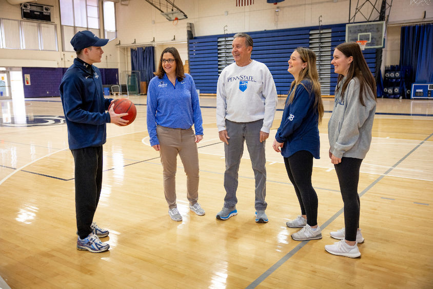 Five people standing on a basketball court
