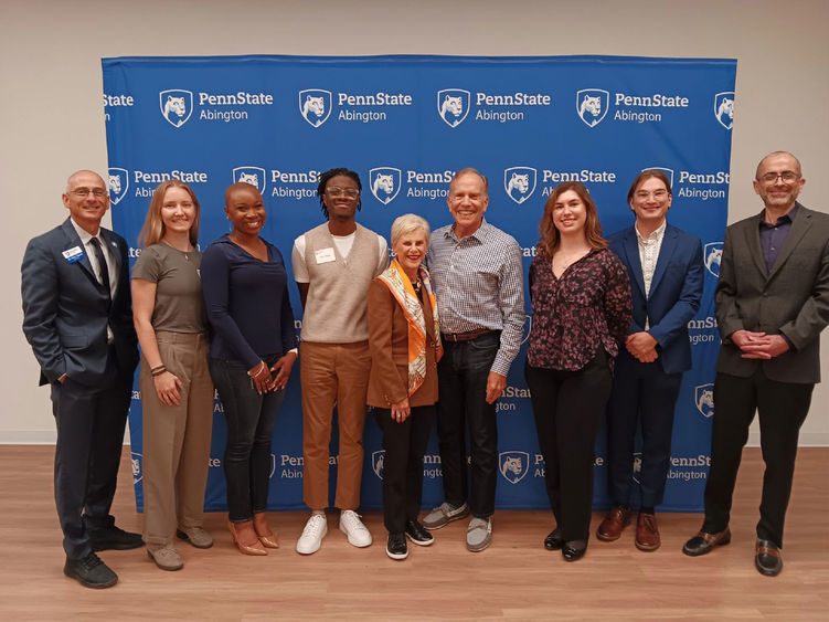 Group of people standing in front of a Penn State Abington banner