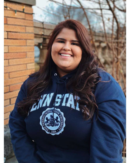 Zeenat Chughtai wearing a Penn State sweatshirt and smiling outside