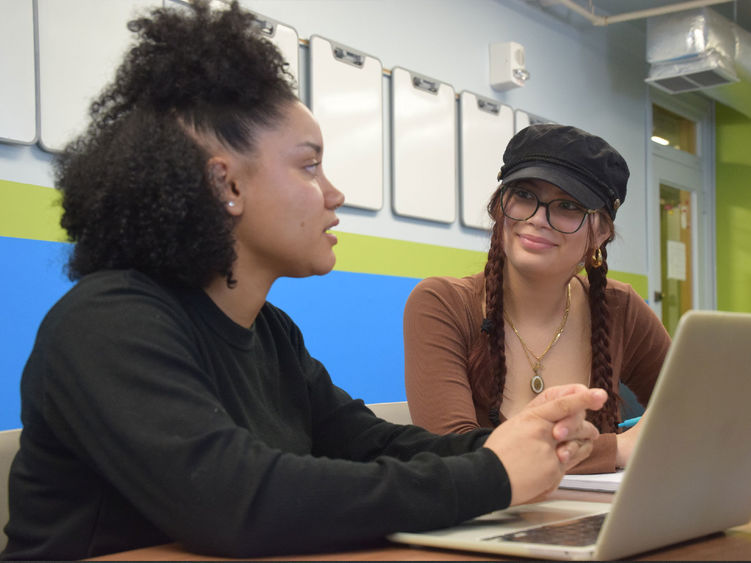 Two student talking with a laptop in front of them