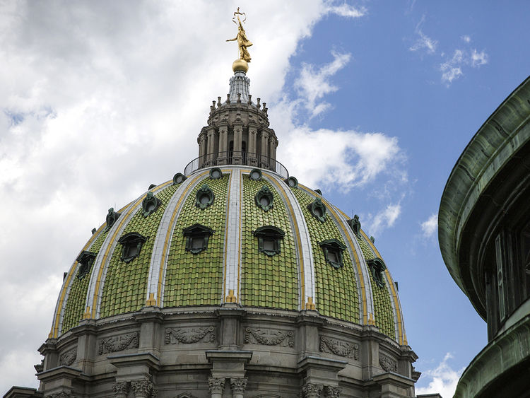 The green and gold exterior of the Pennsylvania Capitol dome against a blue sky with white clouds.