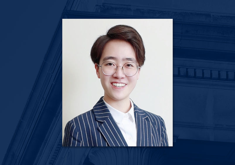 A headshot of a person wearing glasses on a blue background.