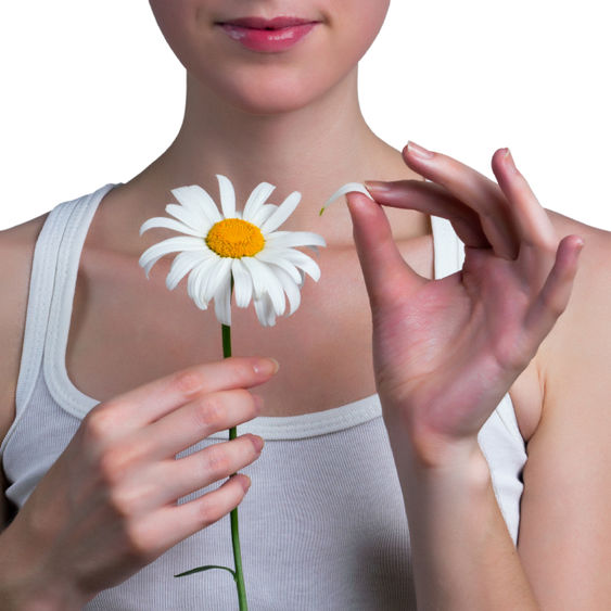 young woman picking petals off daisy young woman picking petals off daisy
