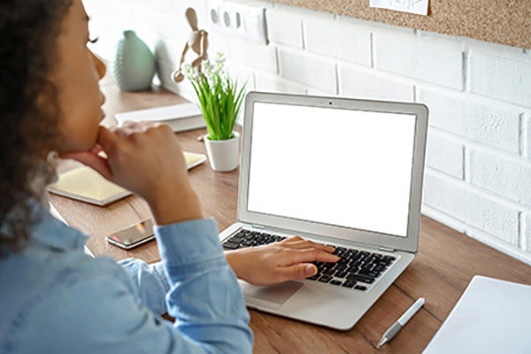 A female student wearing a blue shirt is pictured working at a laptop.