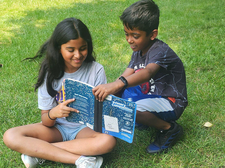 Two children reading a copybook